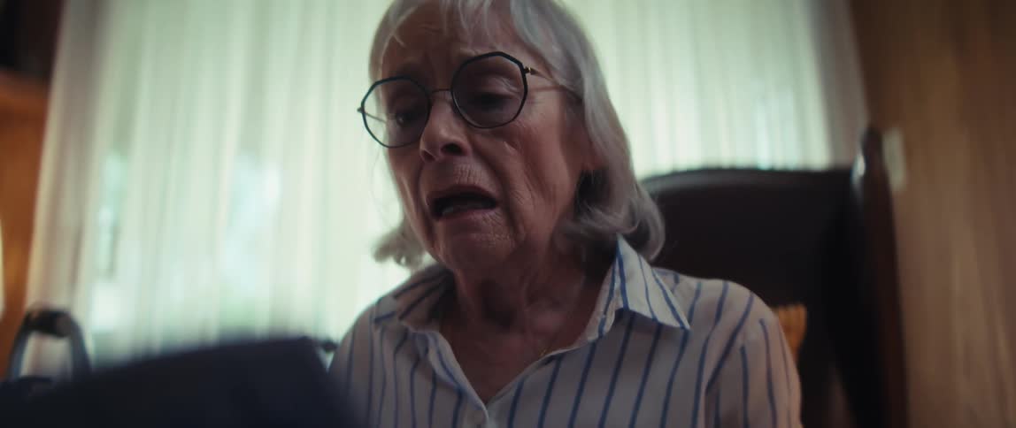 A slow zoom-in captures the emotional distress of an elderly woman as she receives difficult news, with a doctor and loved one offering support