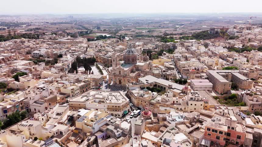 Expansive aerial view of the historic town of Birkirkara in Malta, centered around the magnificent St. Helen's Basilica on a sunny day