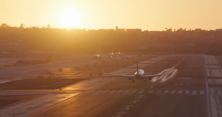 Slow motion shot reveals a passenger jet making a final approach and landing on a runway during a beautiful golden sunset
