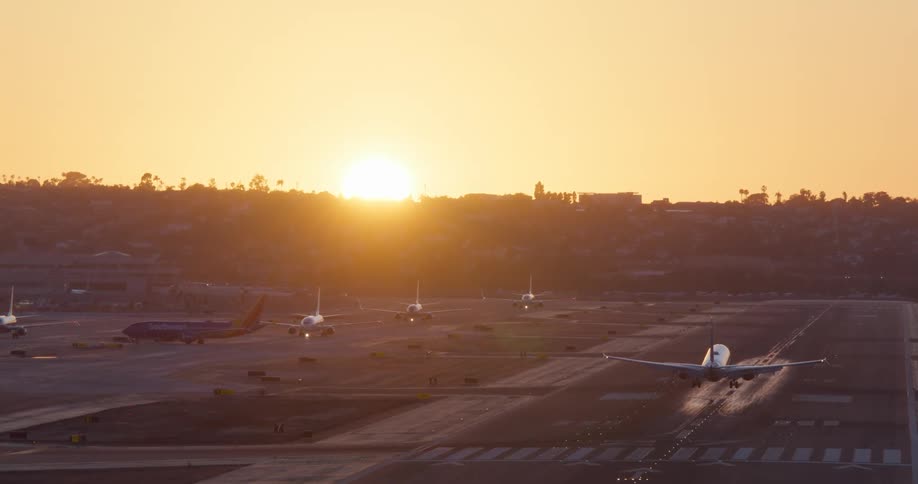 A passenger jet airplane gracefully lands on an airport runway against the backdrop of a beautiful golden sunset