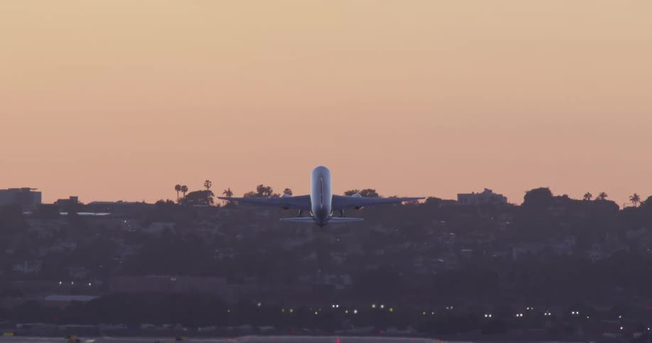 A commercial airliner takes off from a brightly lit runway at sunset, ascending into the golden sky