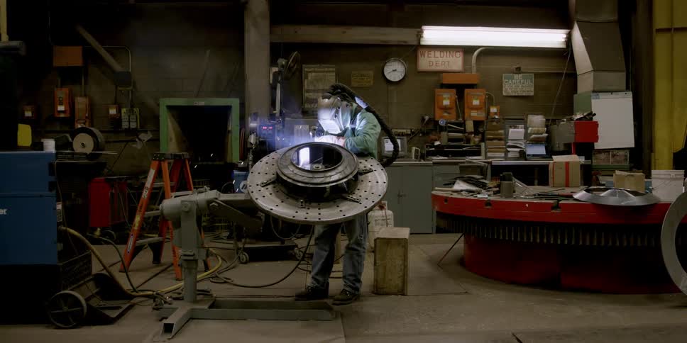 A man is welding in a shop with full gear on