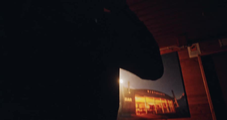 Slow motion shot of a man putting on outdoor gear and a headlamp inside a dark wooden cabin before an adventure