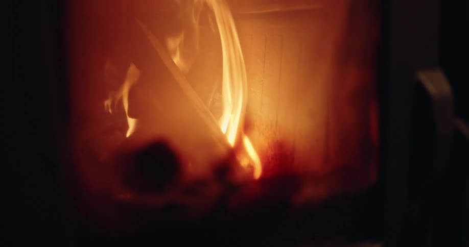 A close-up slow motion shot of a cozy fire with glowing embers and dancing flames burning inside a fireplace