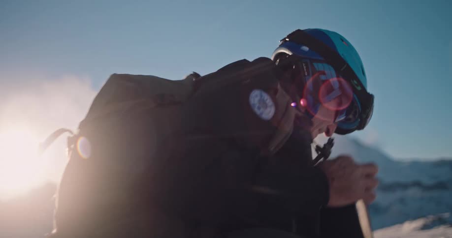 A male backcountry skier prepares his climbing skins on his skis in the snowy mountains at sunrise