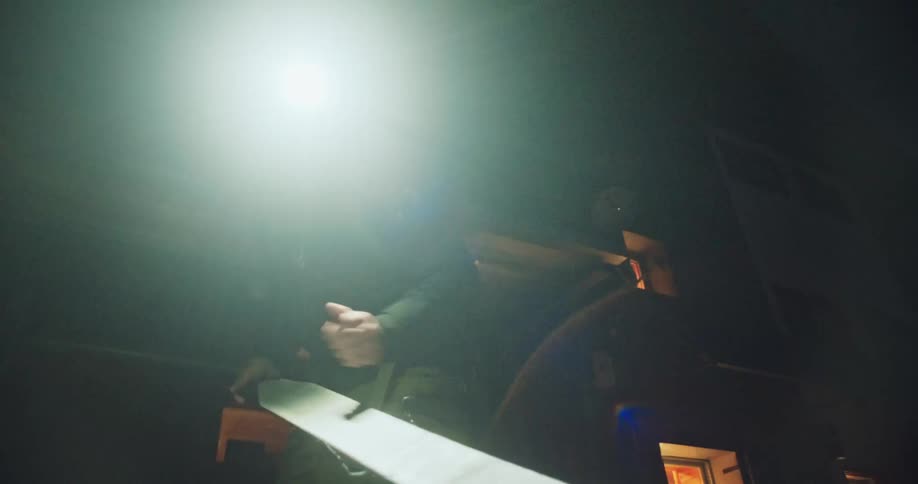 Backcountry skier with a headlamp meticulously prepares his splitboard skins in the dark before a dawn patrol adventure