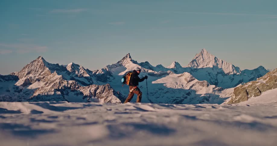 A lone mountaineer treks across a vast, snowy landscape with a stunning mountain range in the background