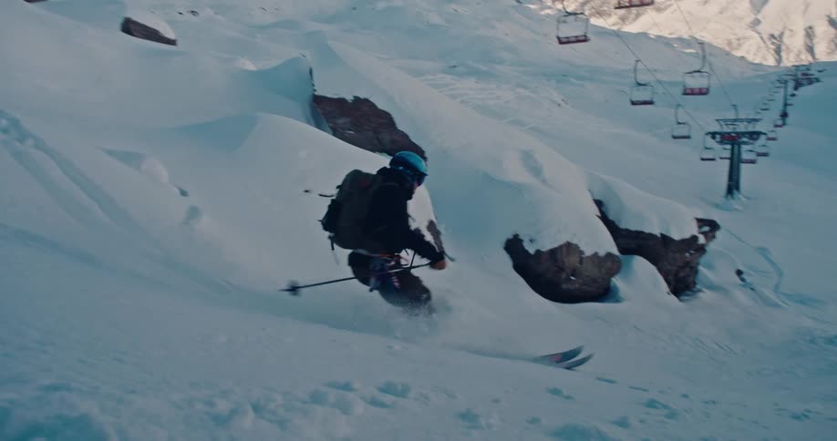 An expert skier carves down a steep, snow-covered mountain face in a breathtaking slow-motion sequence
