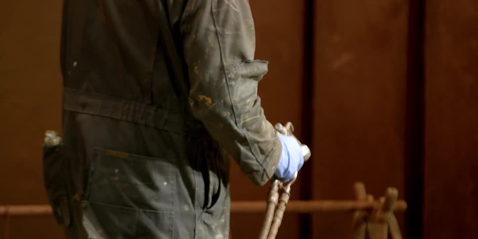 A man spray paints a piece of metal