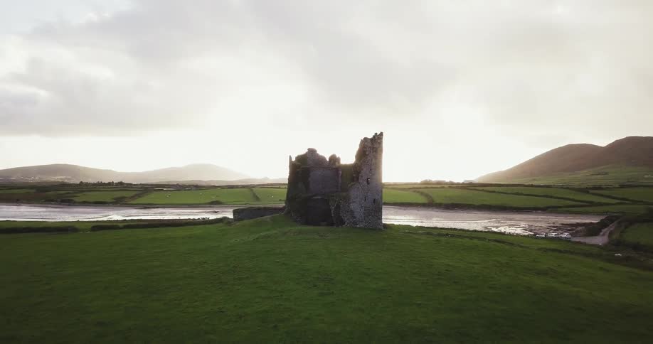 A broken tower sits by the water on a cloudy day
