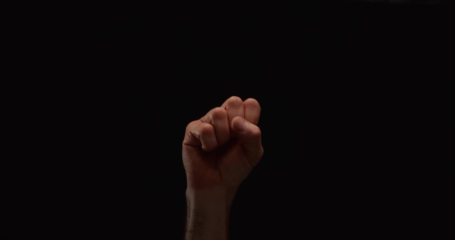 Close-up of a hand making a fist in slow motion against a black background