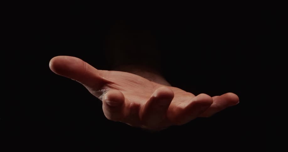 A hand slowly opens from a fist to an open palm and closes again against a dramatic black background