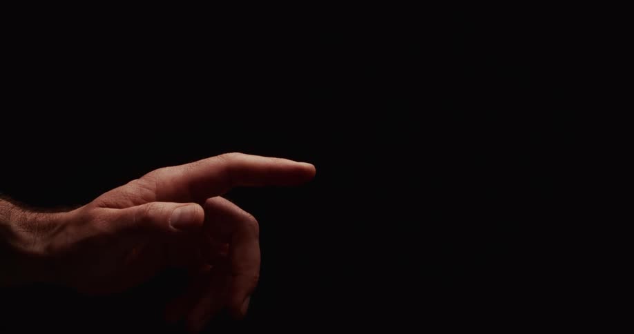 A dramatically lit hand with a twitching index finger points outward against a stark black background
