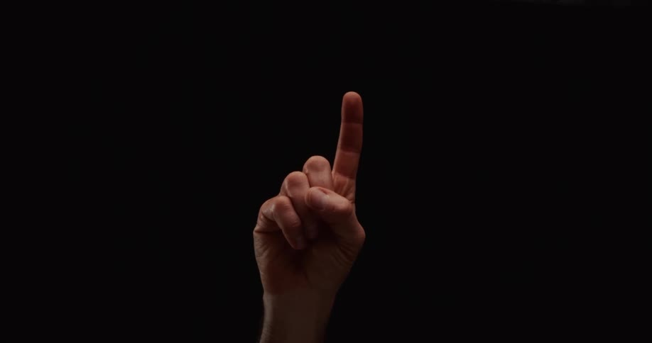 A hand slowly rises and holds up its index finger, signaling the number one against a black background
