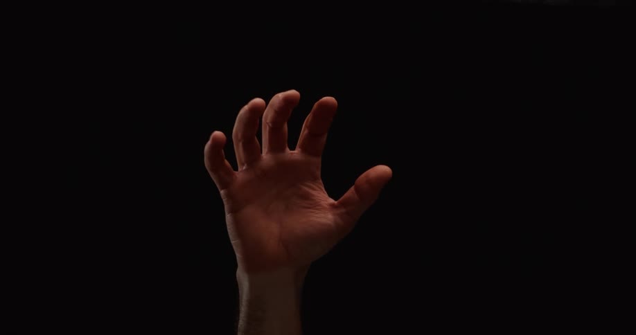 A hand slowly uncurls from a closed fist to reveal an open palm against a stark black background