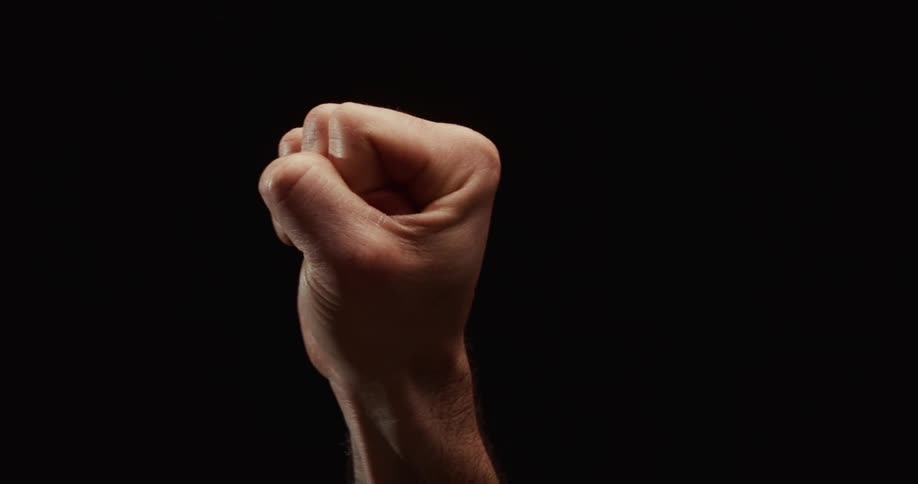 A man's clenched fist, a symbol of protest and strength, slowly rotates in dramatic lighting against a black background