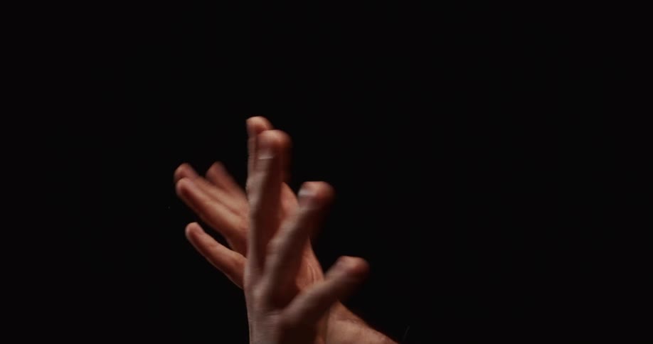 An artistic slow-motion close up of two hands gracefully and sensually interacting against a plain black background