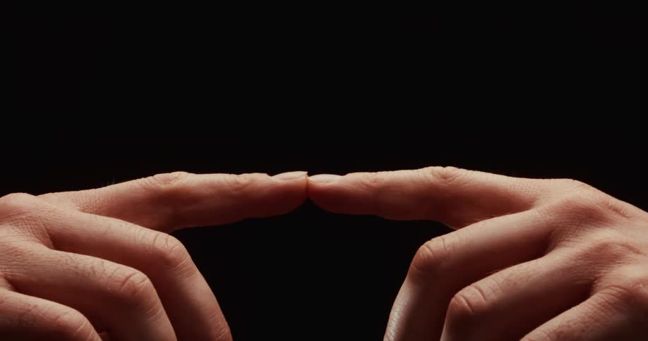 Two index fingers slowly come together and gently touch, symbolizing connection and unity against a black background