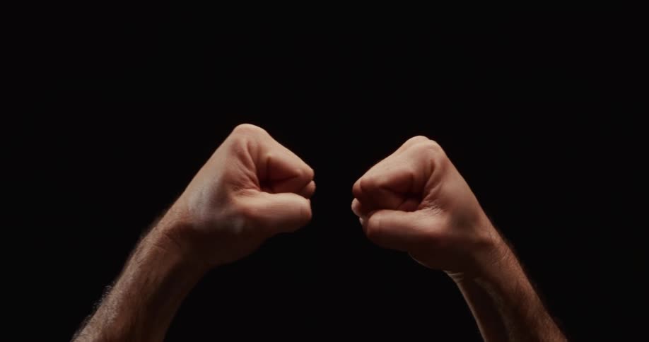 Close-up of two fists bumping together in a gesture of solidarity against a black background