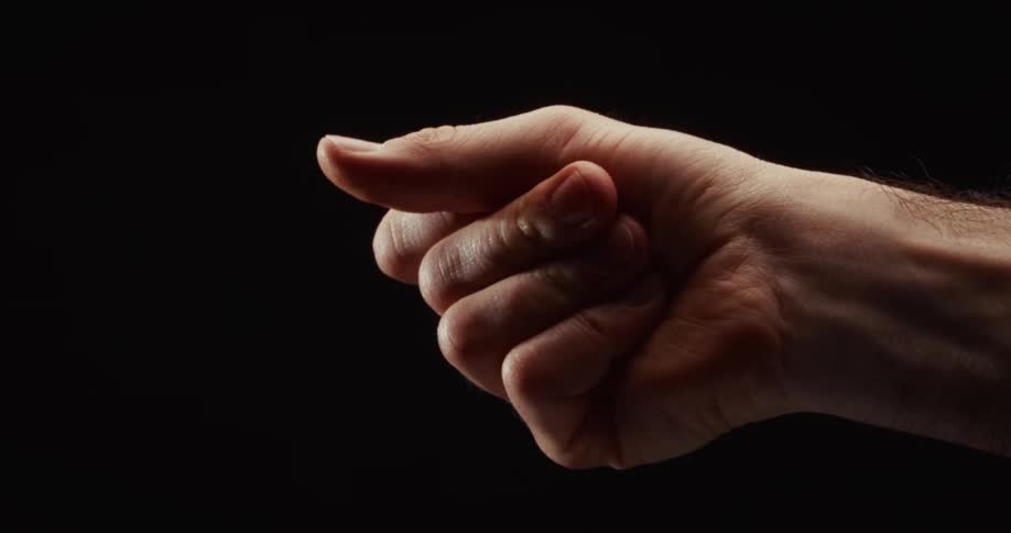 A close-up of a man's hand making the obscene 'fig sign' gesture in slow motion against a black background