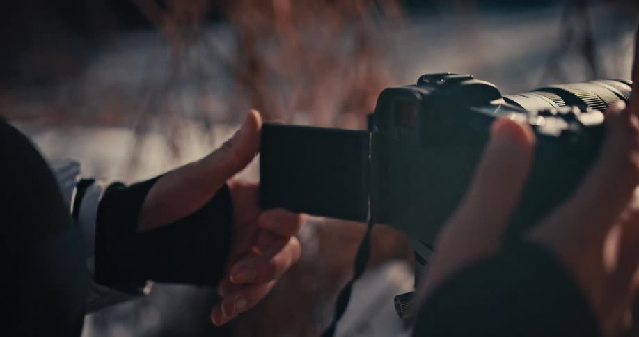 Close-up slow motion shot of a photographer flipping out the camera's LCD screen in a cold, wintry environment
