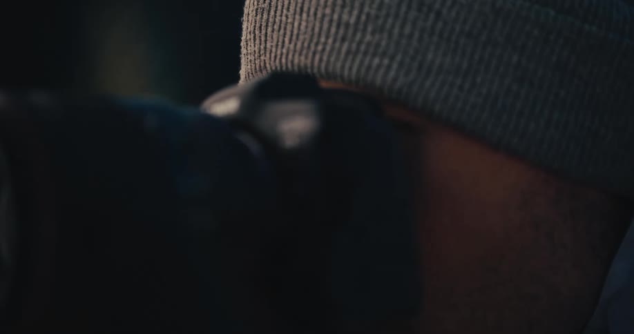 Close-up of a photographer with a Canon EOS R5 camera, focusing intently as a warm lens flare appears