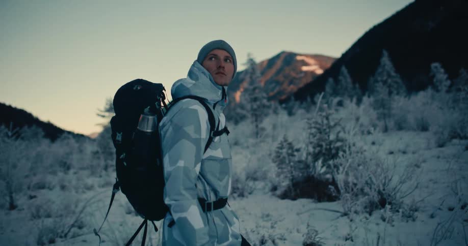 An adventurer hikes through a beautiful frosty mountain landscape at dawn in slow motion