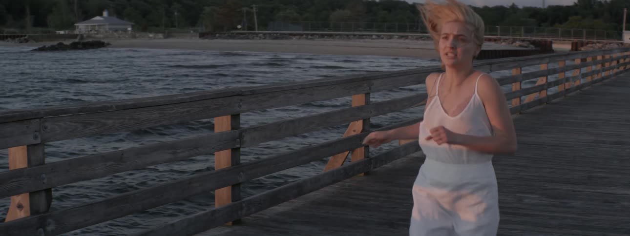 A woman runs on an ocean pier on a windy day