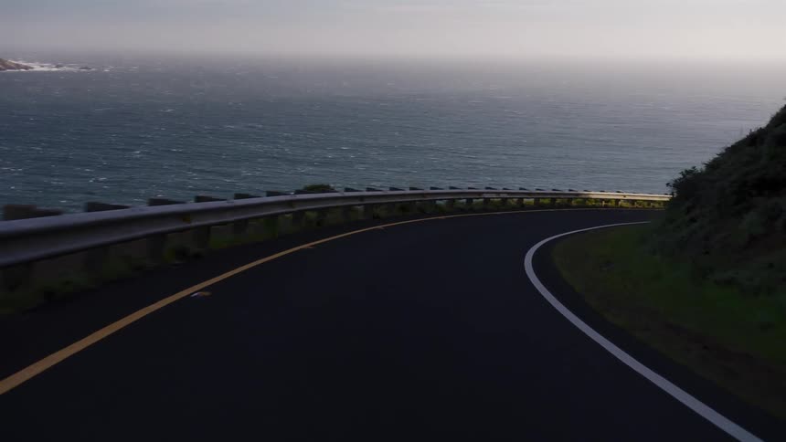 A scenic point-of-view drive on a winding coastal highway as the sun rises over the ocean