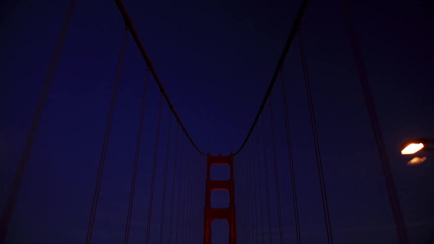 An upward-looking point-of-view shot while driving over the Golden Gate Bridge at dusk