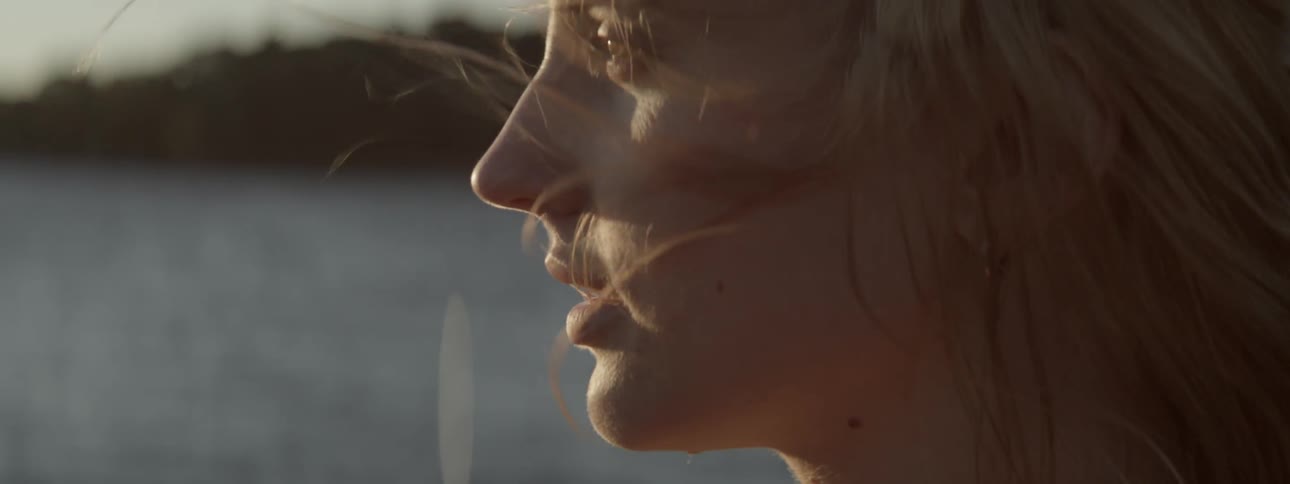 A woman's hair blows around her face as she looks out at the water