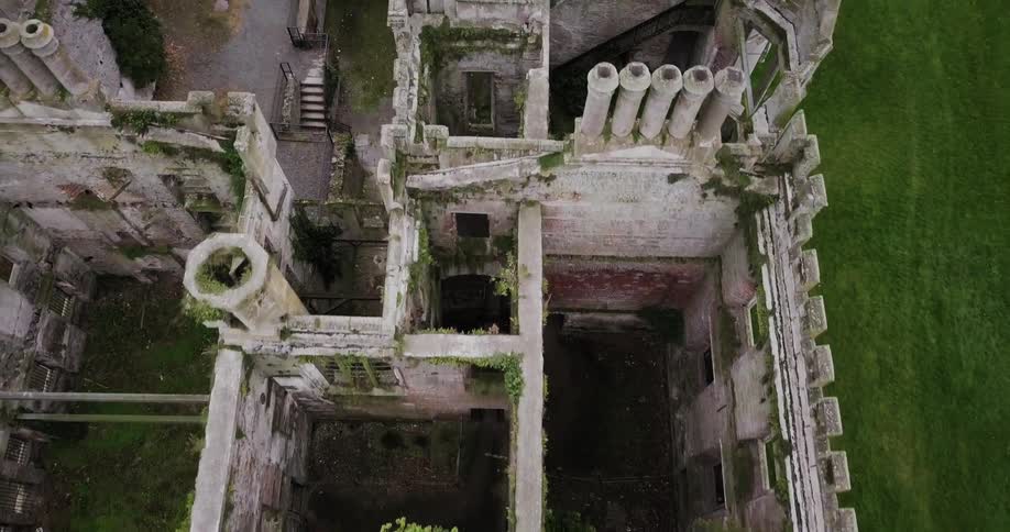 The building is missing a roof and surrounded by green