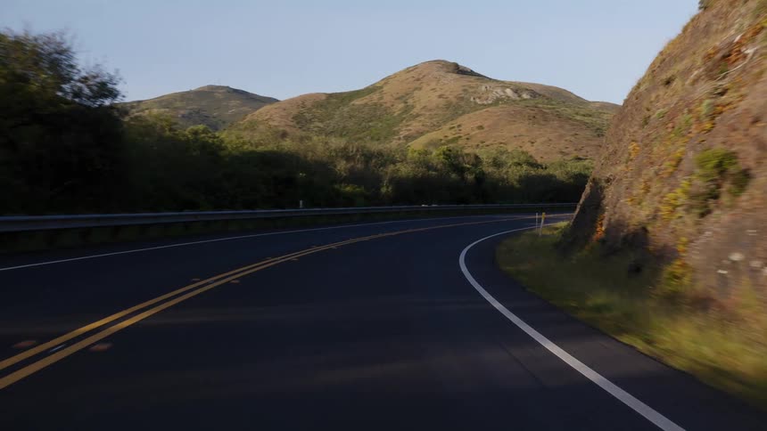 A smooth point-of-view drive on a scenic, curving highway through rolling hills