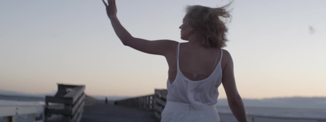 A woman raises her hand as she walks