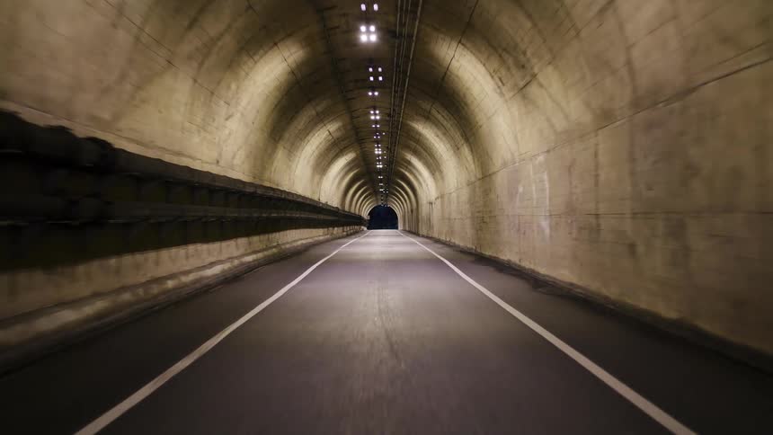 A steady point-of-view journey through a long, dimly lit, arched tunnel towards the light at the end