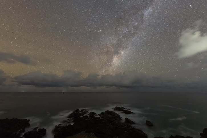 A stunning timelapse captures the Milky Way galaxy moving across the starry night sky above a rocky ocean coastline
