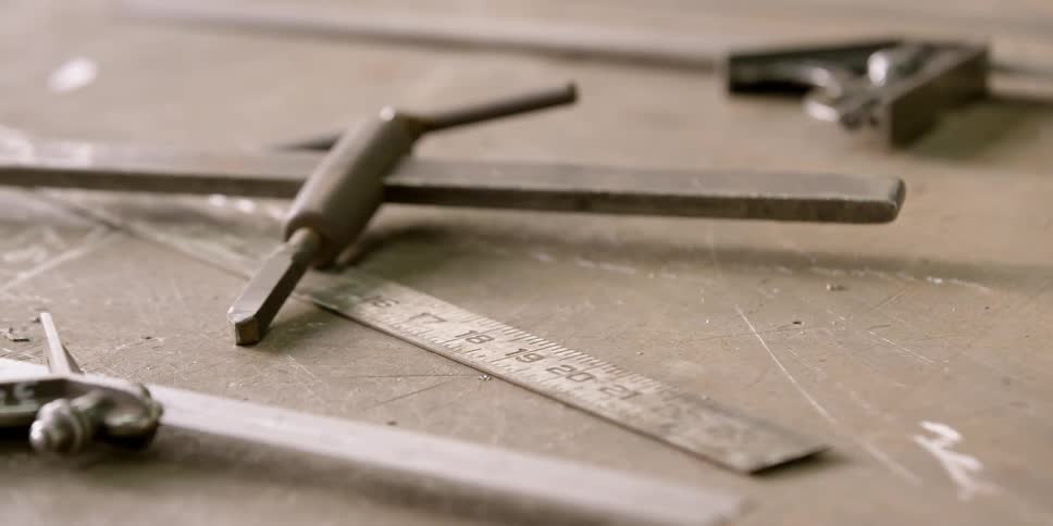 A t wrench drill bit and ruler sit on a workbench