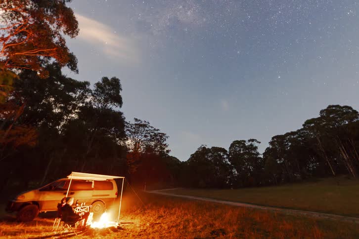 A stunning night-to-dawn timelapse shows campers enjoying a warm fire beside their van as the Milky Way and clouds drift across the starry sky