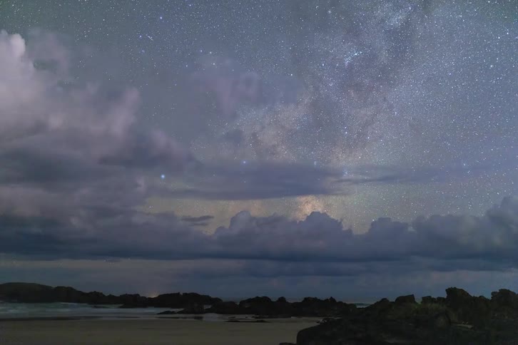 A time-lapse of a powerful lightning storm flashing over the ocean with the Milky Way visible in the night sky
