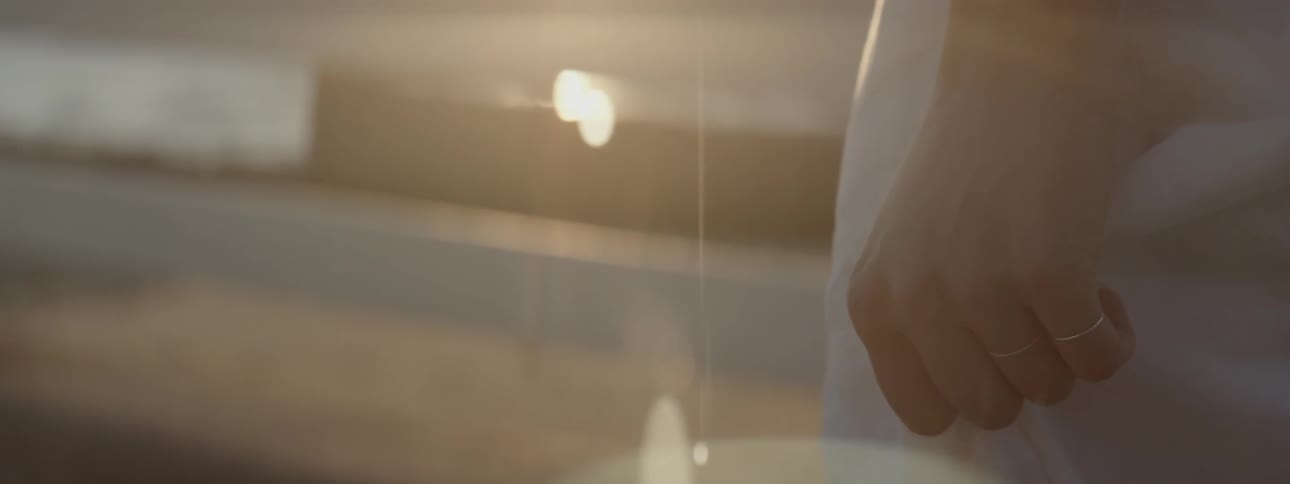 A woman closes her hand at sunset
