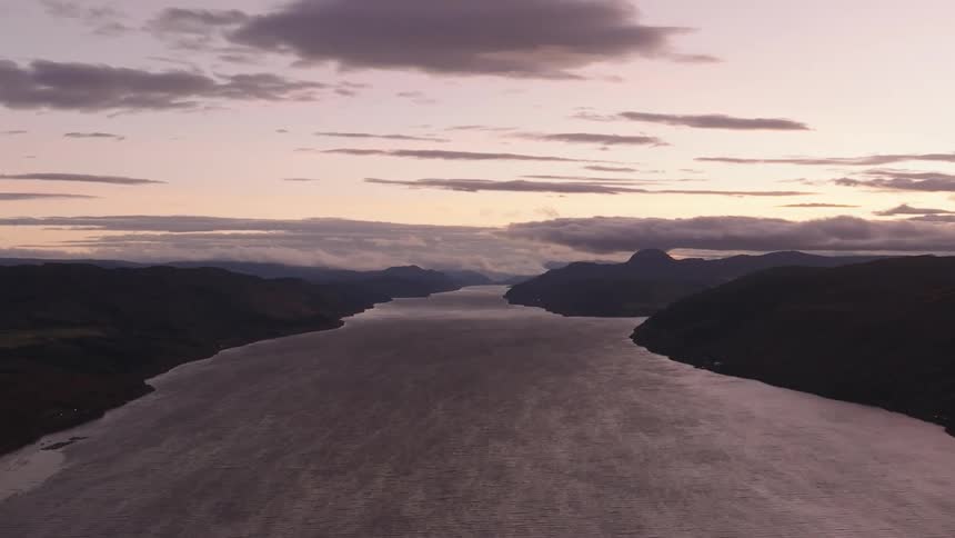 A stunning aerial view of Loch Ness in Scotland, nestled between the highlands under a beautiful sunset sky