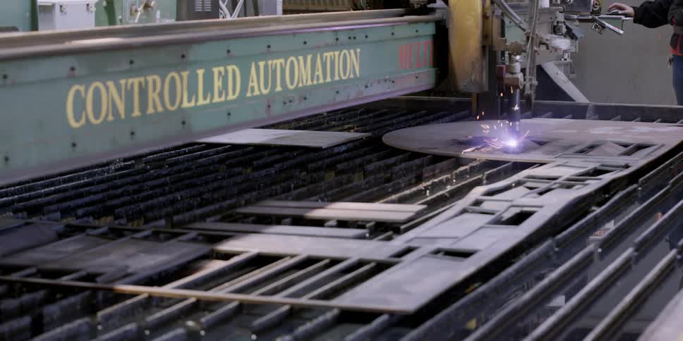 Automated machinery cuts a piece of metal in a factory