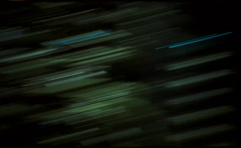 Vintage Super 16mm footage shows a chaotic, abstract journey through a city at night, captured in colorful, streaking light trails