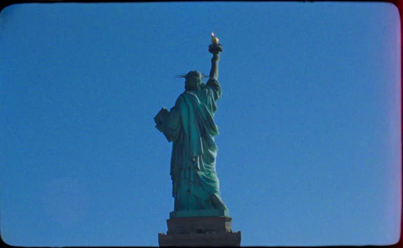 Vintage film captures the Statue of Liberty standing tall against a vibrant, clear blue sky