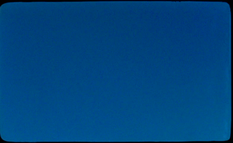 Vintage home movie footage captures a low angle shot of the Statue of Liberty against a vibrant blue sky