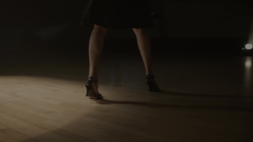A woman wearing high heels walks along the wooden floor