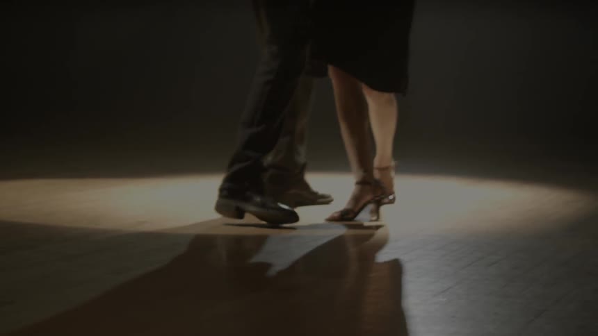 A man and woman dance on a wood floor