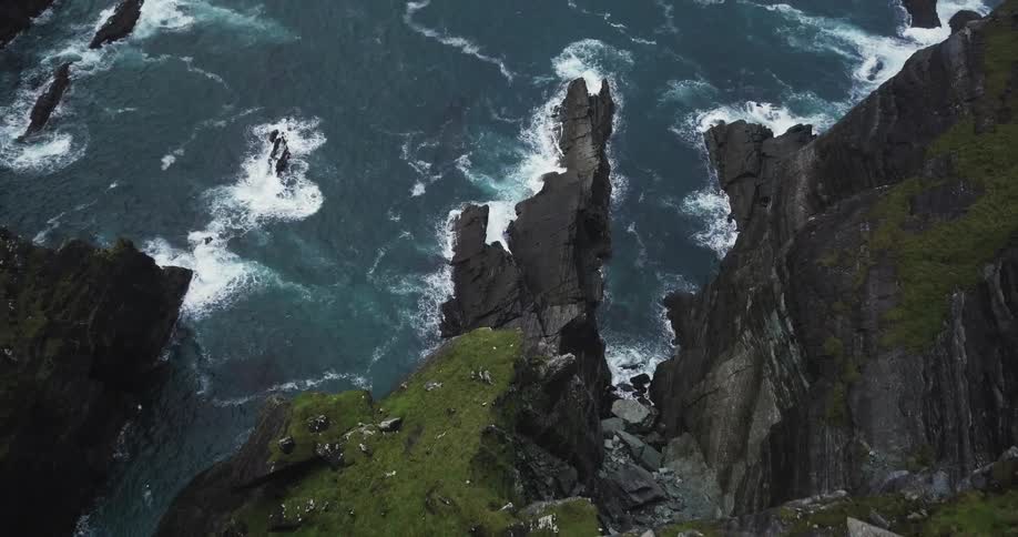 Waves splash against the rocks below the cliff