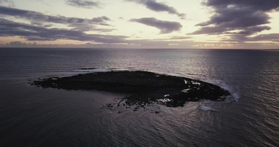 Water laps at the edges of a flat island in the middle of the ocean