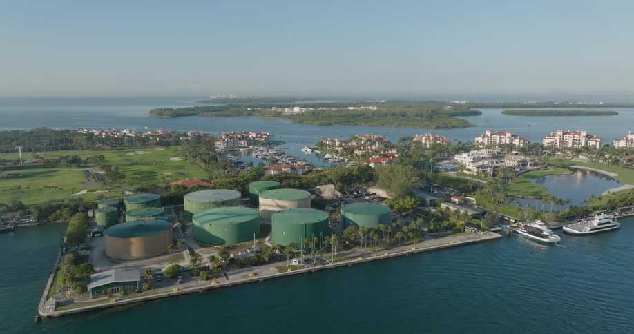 An aerial view shows industrial storage tanks on the water next to the exclusive and luxurious Fisher Island, with its golf course and marina